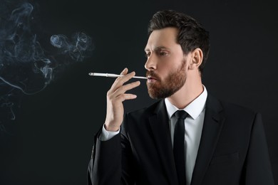 Man using long cigarette holder for smoking on black background