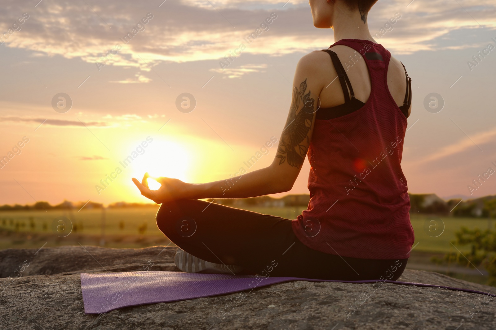 Photo of Young woman practicing zen yoga at sunrise outdoors, closeup