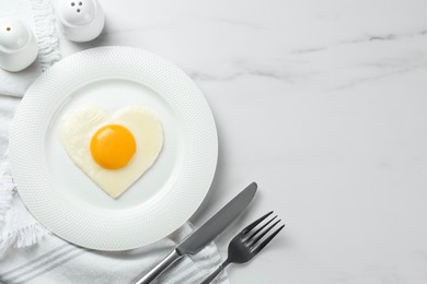 Photo of Heart shaped fried egg served on white marble table, flat lay. Space for text