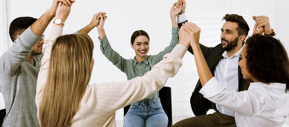 Image of People holding hands at group therapy session indoors. Banner design