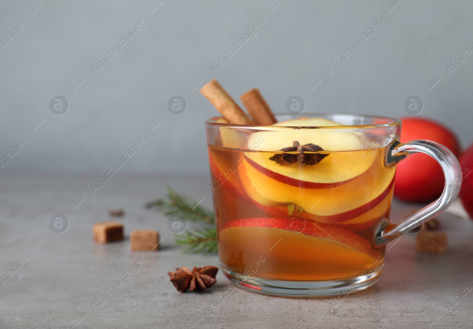 Photo of Aromatic hot mulled cider on grey table. Space for text