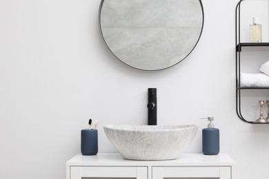 Different bath accessories and personal care products near sink on bathroom vanity