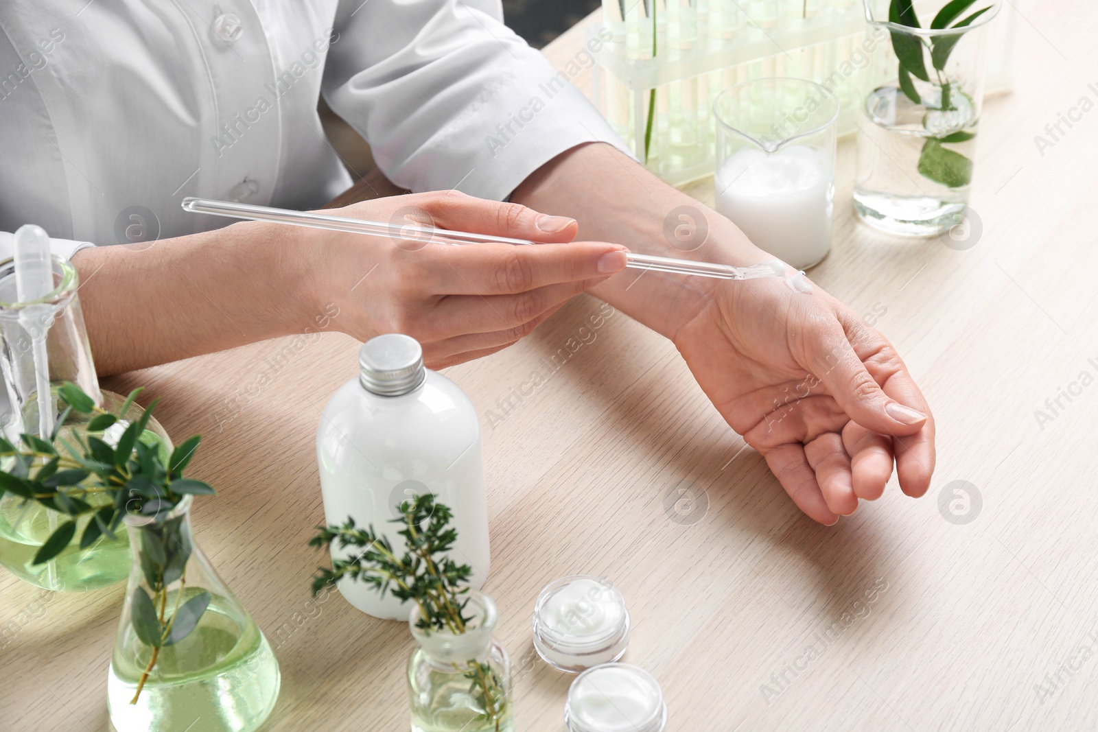 Photo of Woman applying natural cream onto hand in cosmetic laboratory, closeup