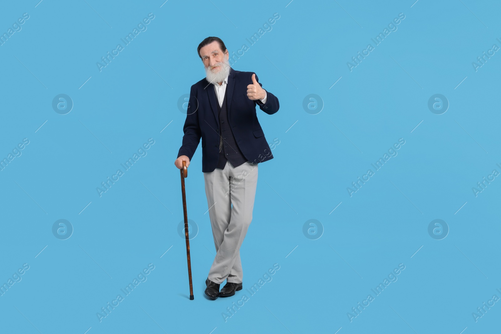 Photo of Senior man with walking cane showing thumb up on light blue background