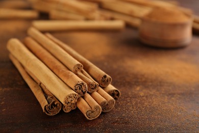 Aromatic cinnamon sticks and powder on wooden table, closeup. Space for text