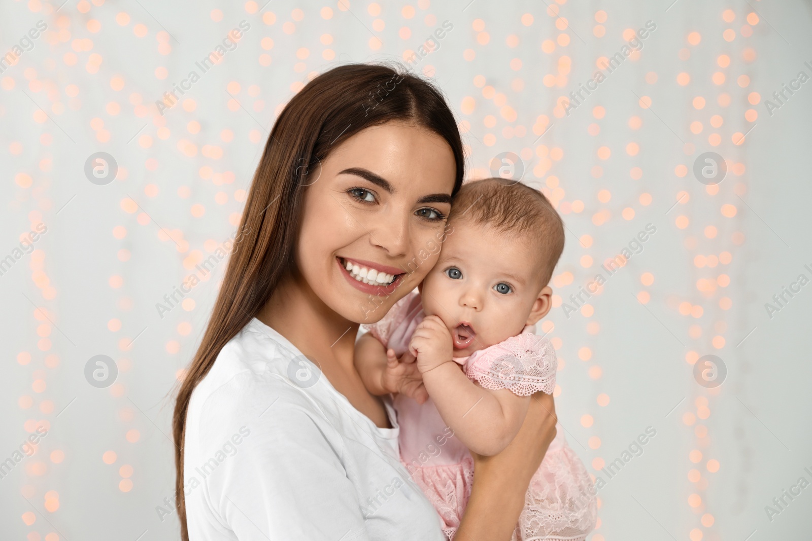 Photo of Portrait of happy mother with her baby against blurred lights