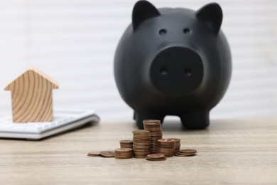 House model, calculator, piggy bank and stacked coins on wooden table