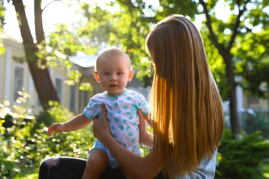 Teen nanny with cute baby outdoors on sunny day