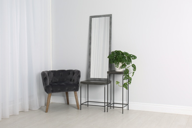 Photo of Modern interior with large mirror and comfortable armchair near white wall