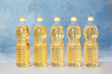 Photo of Row of plastic bottles with oil on color background