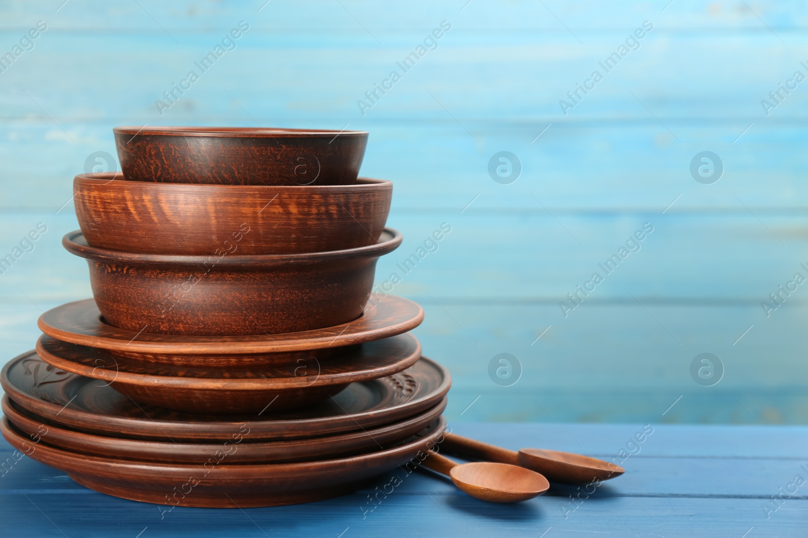 Photo of Set of clay utensils on blue wooden table. Space for text