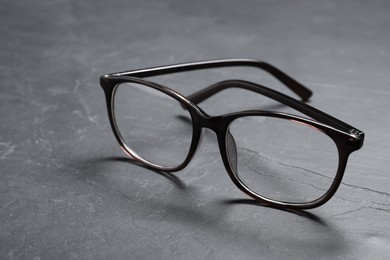 Photo of Glasses in stylish frame on black table, closeup