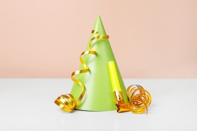 Photo of Colorful party hat, streamers and blower on white table. Birthday celebration