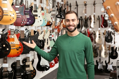 Young shop assistant near guitars in music store