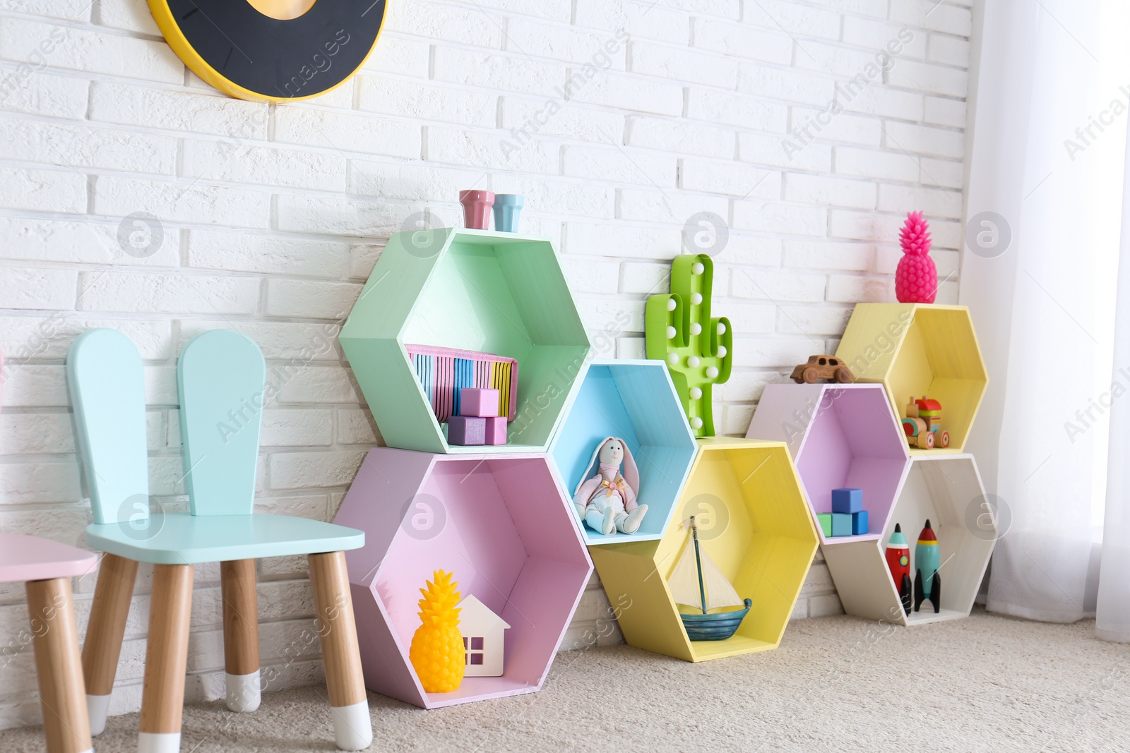 Photo of Child room interior with colorful shelves near brick wall