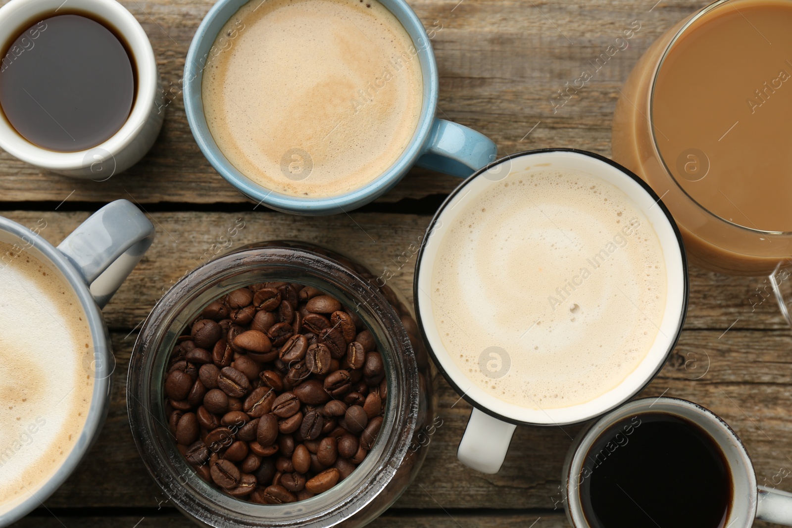 Photo of Different coffee drinks in cups and beans on wooden table, flat lay