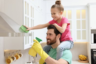 Photo of Spring cleaning. Father and daughter tidying up in kitchen together