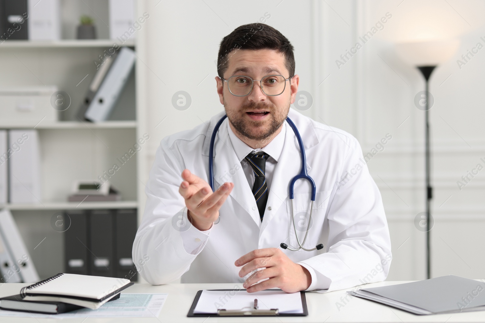 Photo of Emotional doctor working at white table in clinic