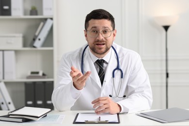 Emotional doctor working at white table in clinic