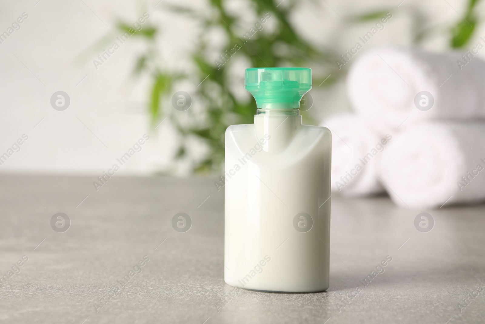 Photo of Mini bottle of cosmetic product on light grey table against blurred background, closeup. Space for text