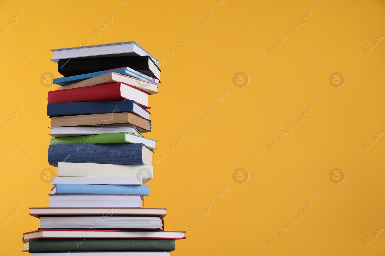 Photo of Stack of hardcover books on orange background. Space for text