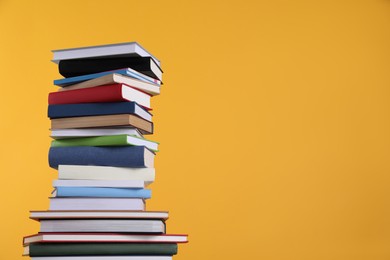 Photo of Stack of hardcover books on orange background. Space for text