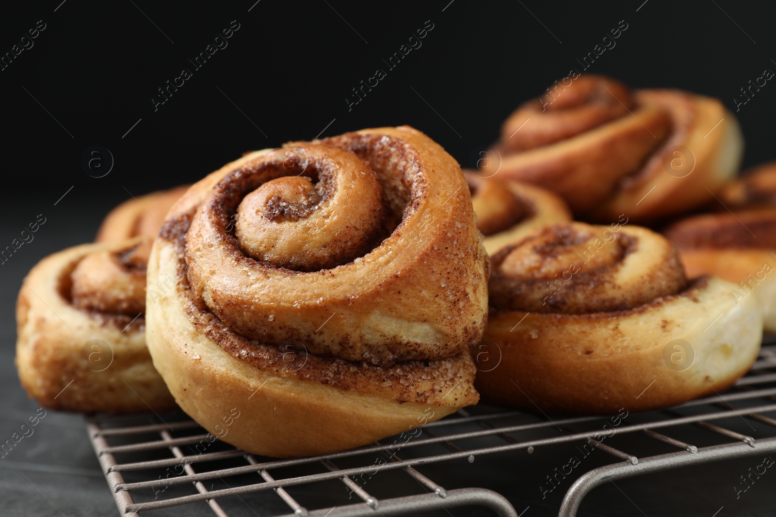 Photo of Tasty cinnamon rolls on black table, closeup