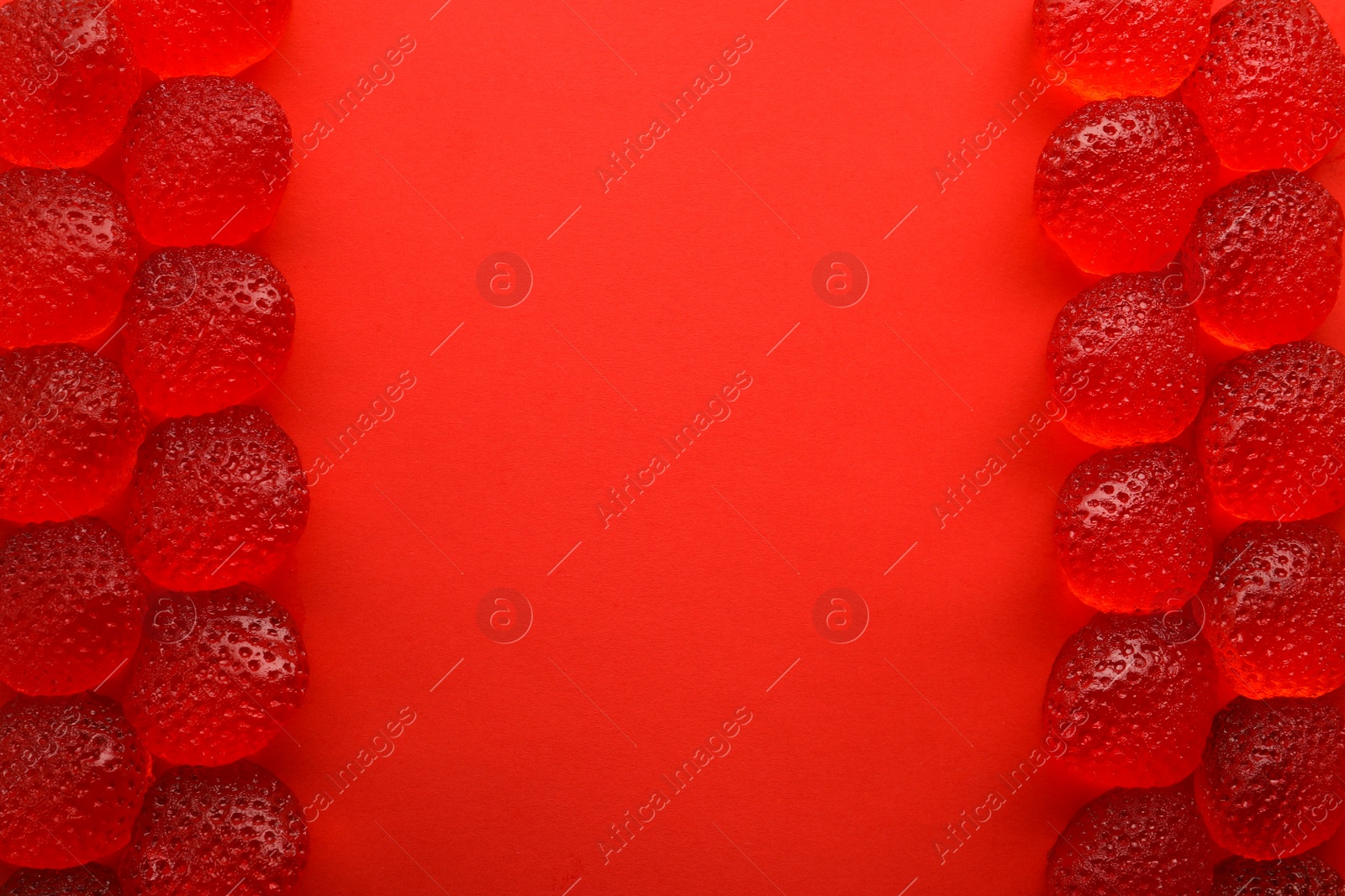 Photo of Delicious gummy strawberry candies on red background, flat lay. Space for text