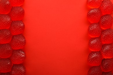 Photo of Delicious gummy strawberry candies on red background, flat lay. Space for text