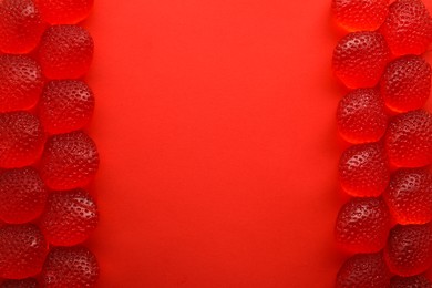 Delicious gummy strawberry candies on red background, flat lay. Space for text