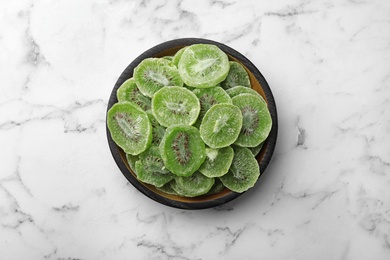 Photo of Bowl with slices of kiwi on marble background, top view. Dried fruit as healthy food