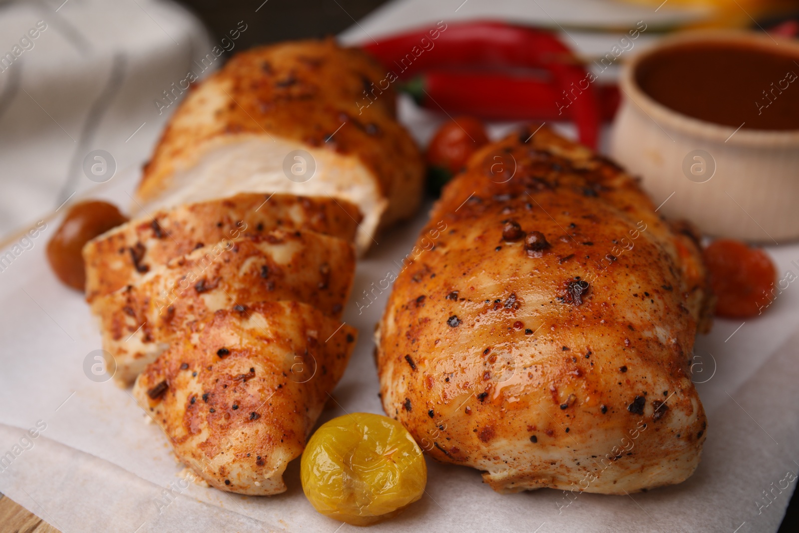 Photo of Baked chicken fillets and marinade on table, closeup