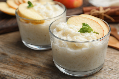 Delicious rice pudding with apple on wooden table, closeup
