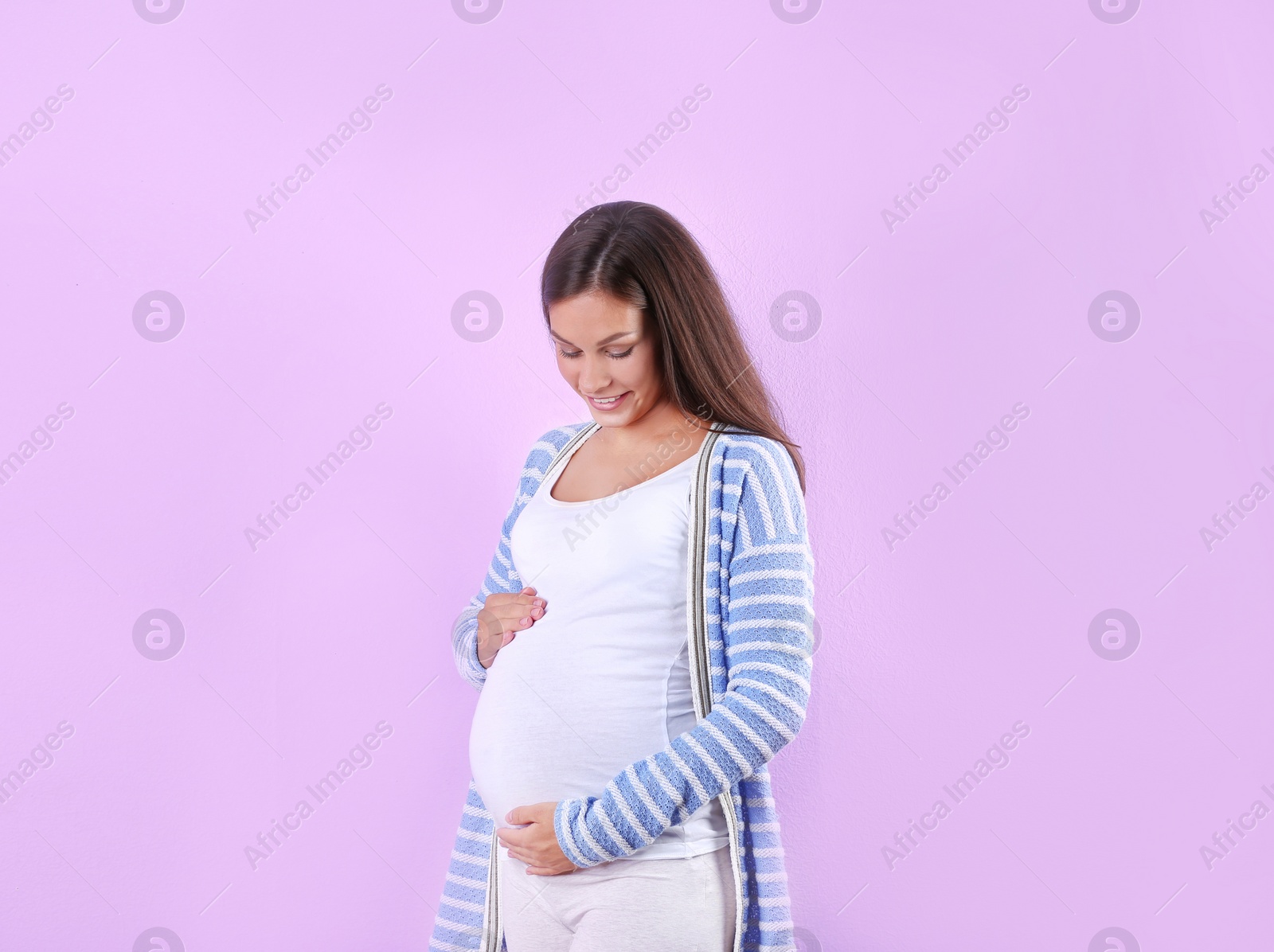 Photo of Happy pregnant woman posing on color background