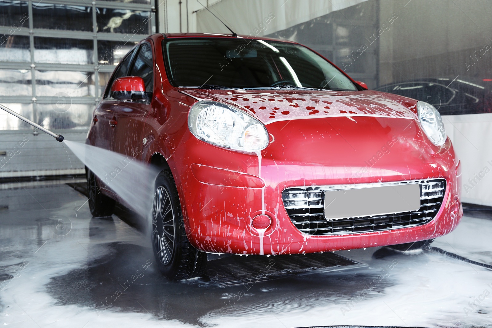 Photo of Cleaning modern automobile with high pressure water jet at car wash