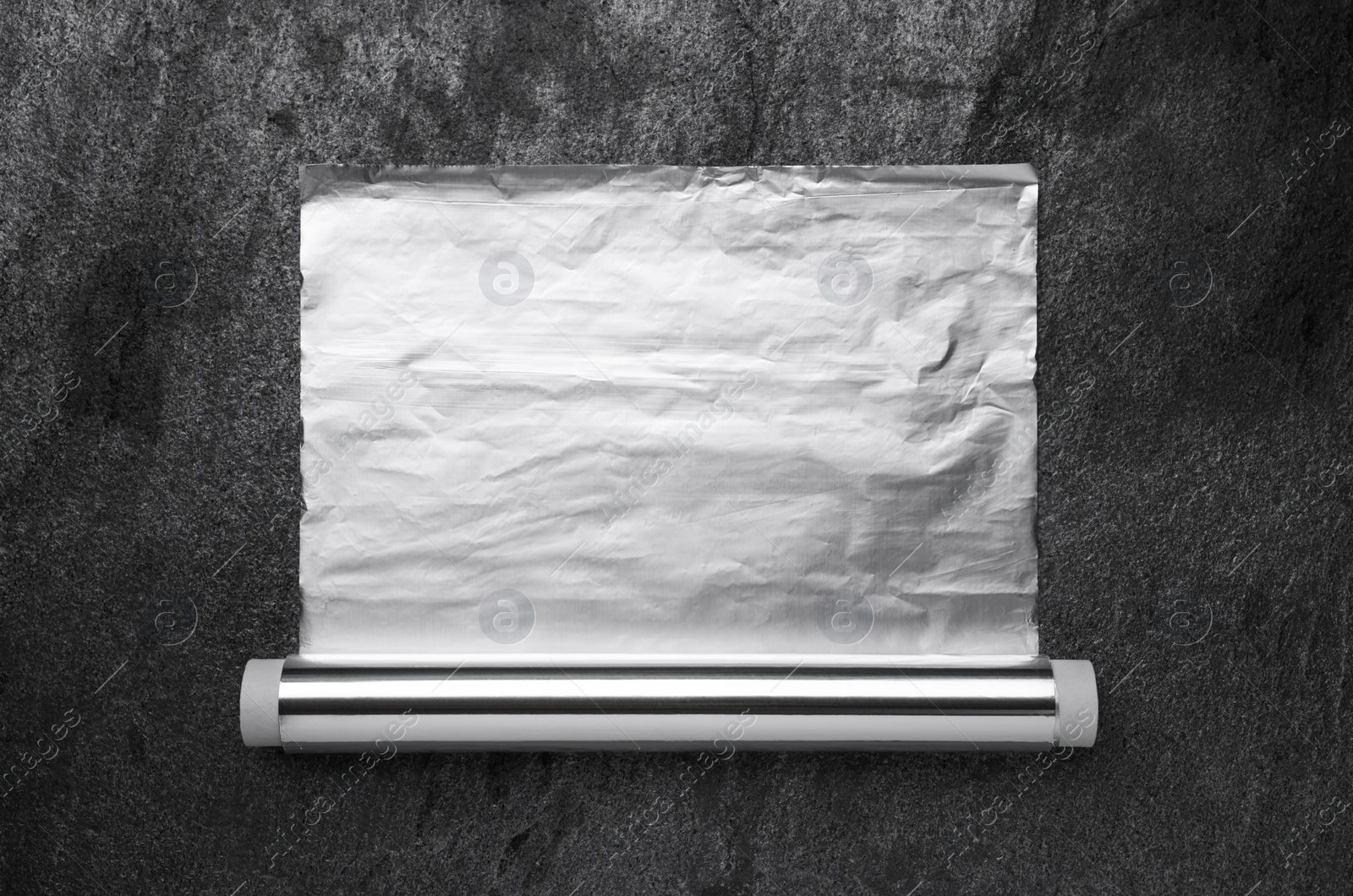 Photo of Roll of aluminum foil on grey table, top view