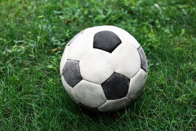 Photo of Dirty soccer ball on fresh green grass outdoors, closeup