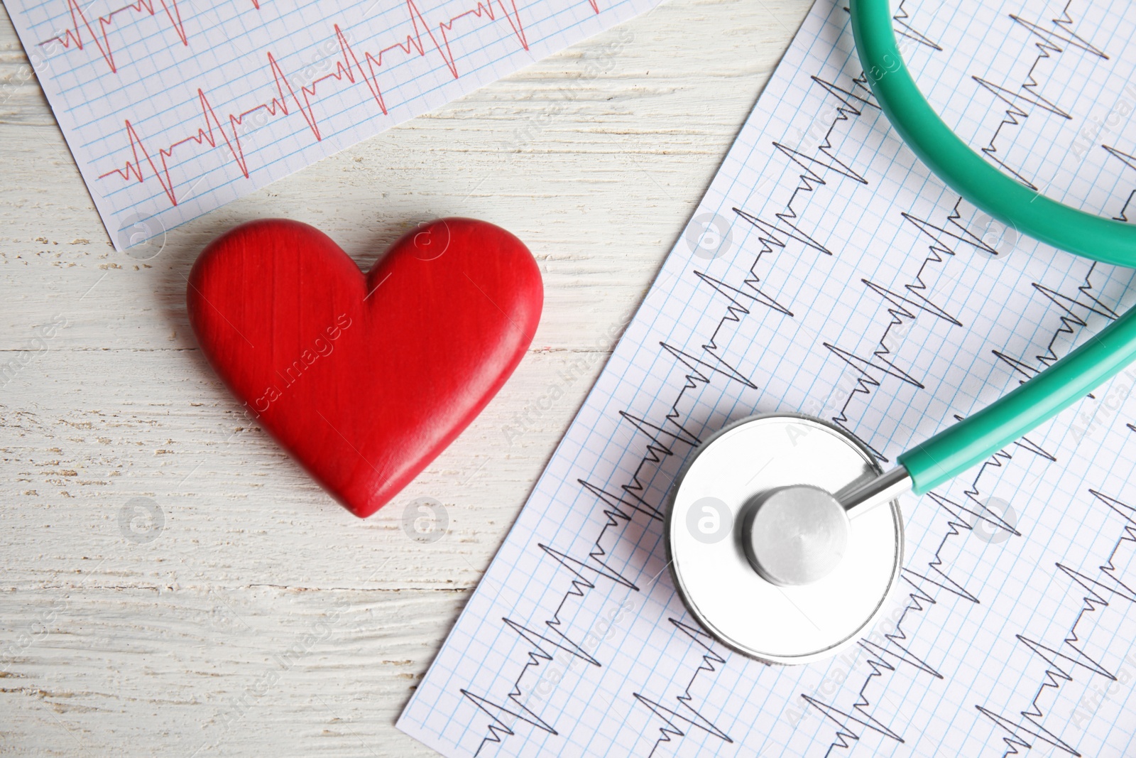 Photo of Stethoscope, red heart and cardiograms on table, top view. Cardiology concept