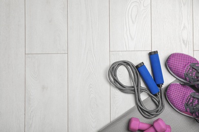 Photo of Flat lay composition with jump rope, gym equipment and space for text on wooden background