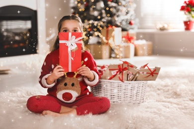 Cute little girl holding gift from Christmas advent calendar at home, space for text