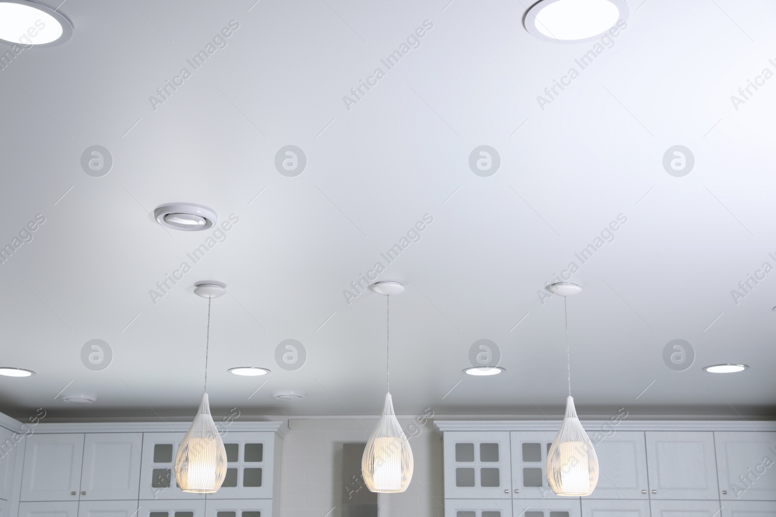 Photo of Modern pendant lamps on white ceiling indoors