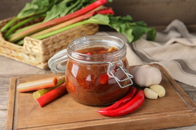 Tasty rhubarb sauce and ingredients on wooden table