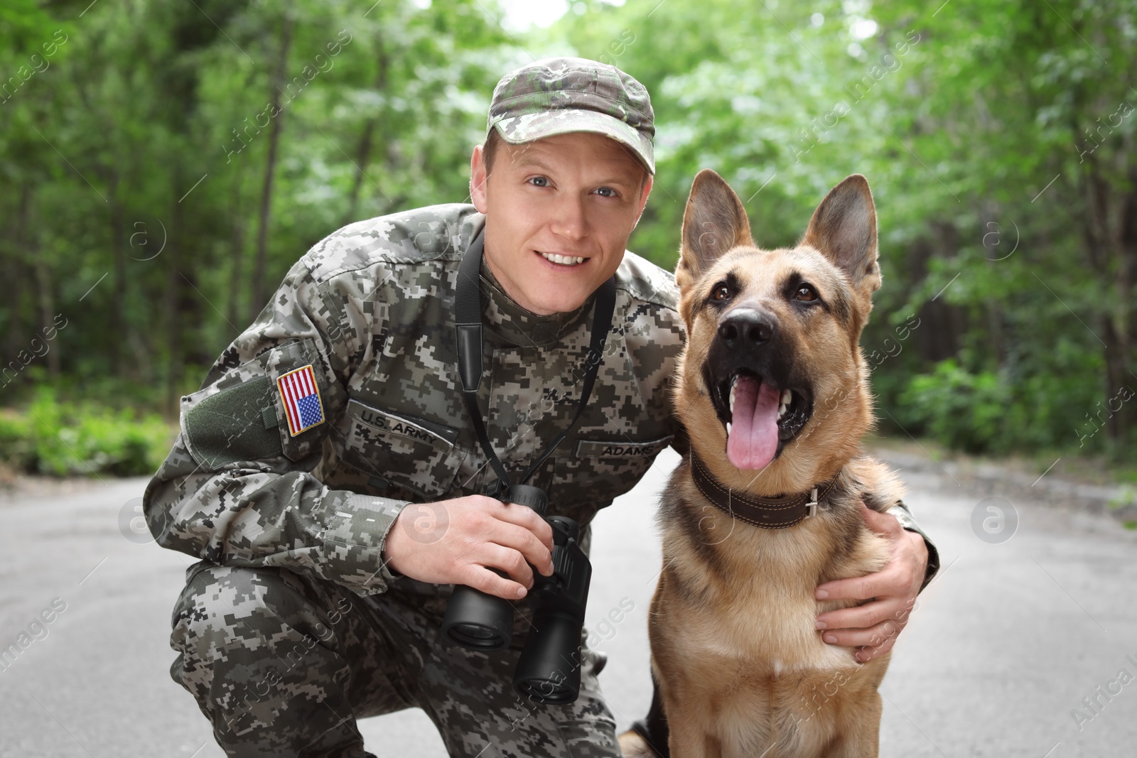 Photo of Man in military uniform with German shepherd dog, outdoors