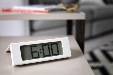 Digital alarm clock on table in living room. Time of day