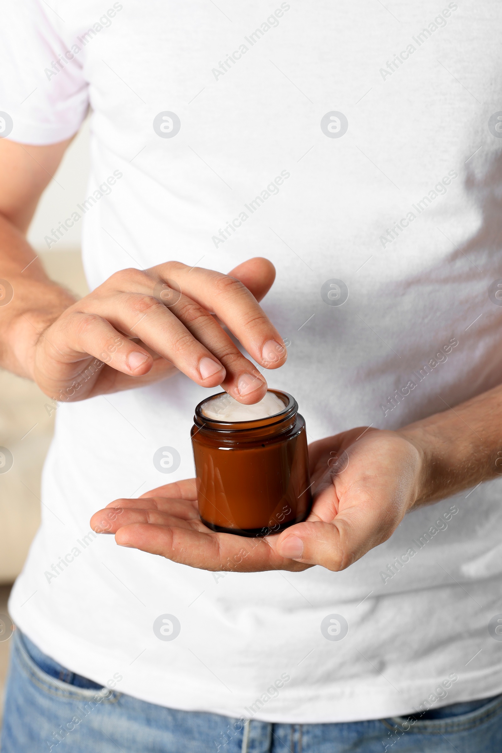 Photo of Man holding jar of hand cream, closeup view