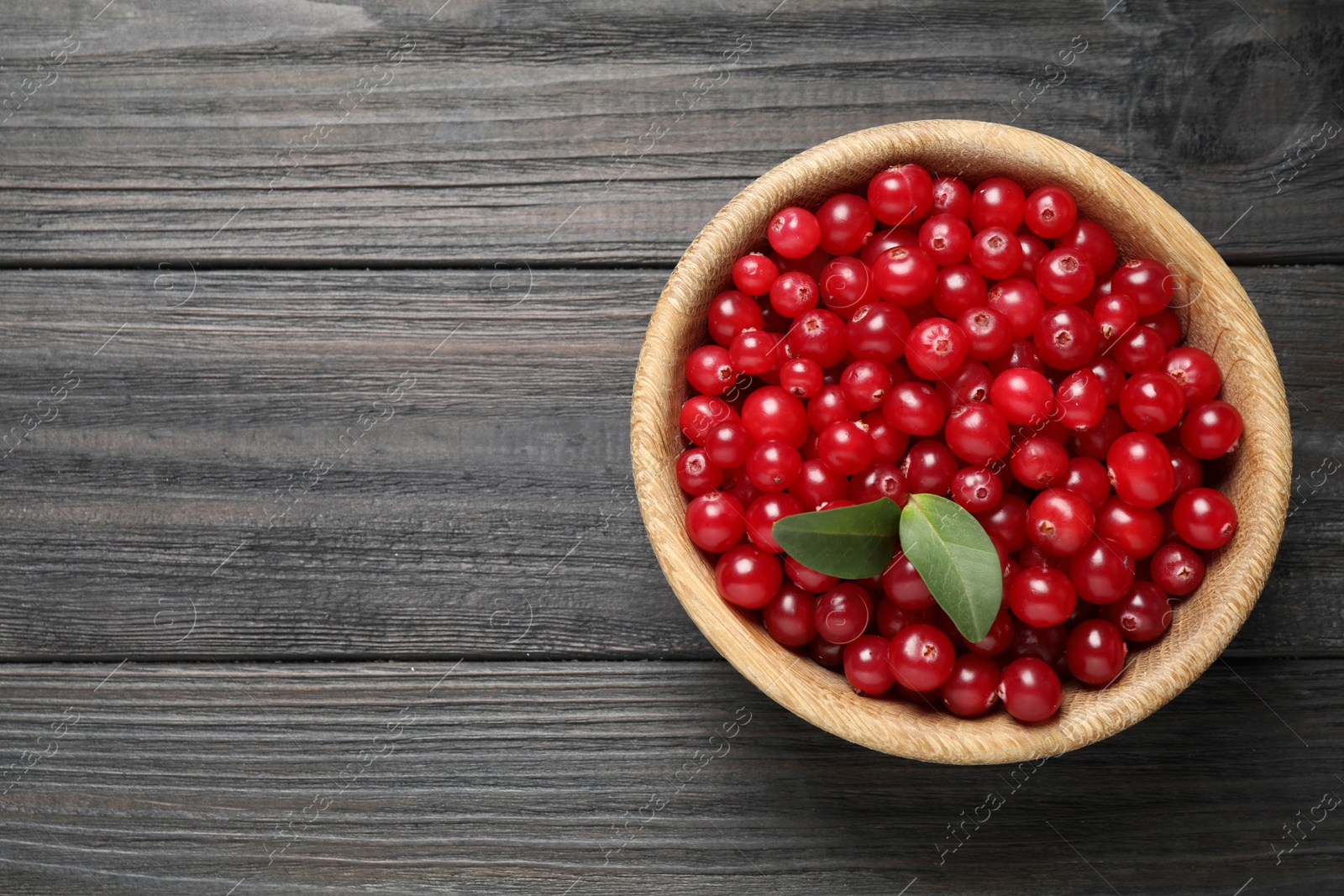 Photo of Ripe fresh cranberry on grey wooden table, top view. Space for text