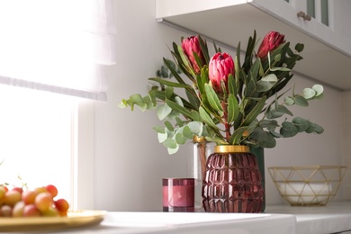 Beautiful protea flowers on countertop in kitchen, space for text. Interior design