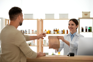 Pharmacist giving medicine to customer in drugstore