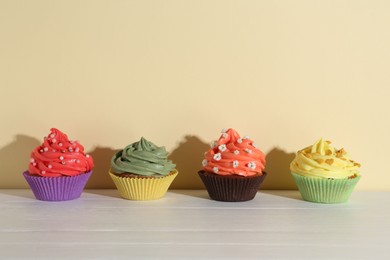 Photo of Delicious cupcake with bright cream on white wooden table. Space for text