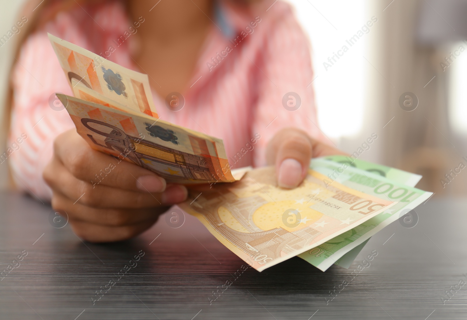 Photo of Woman with Euro banknotes at table indoors, closeup